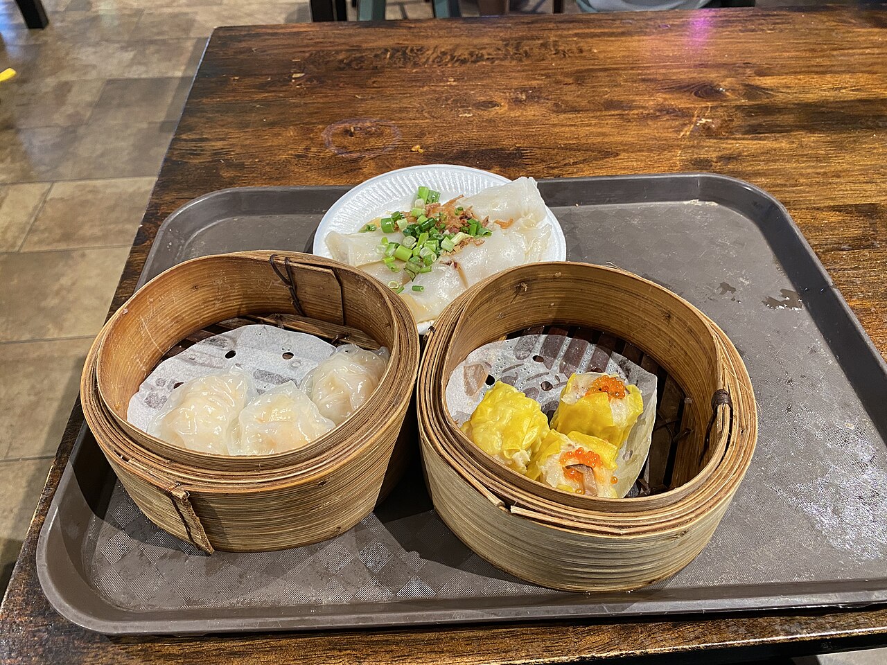 A dim sum trio of har gow, siu mai and rice noodle roll on a plate