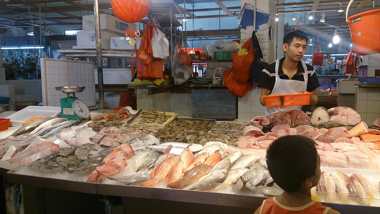 A fishmonger's stall displaying fresh whole fish on ice at a Singapore wet market