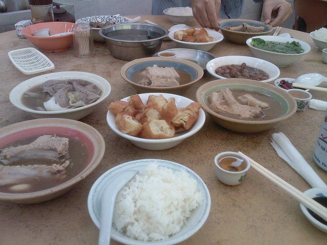 Bowls of Singapore-style bak kut teh pork rib soup served with you tiao, rice and side dishes