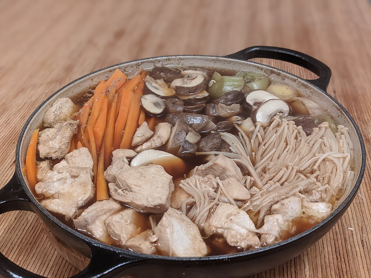 A mushroom hot pot showcasing enoki, oyster and other mushroom varieties in clear broth